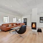 Wohnzimmer mit Sofa, Kamin und Küche im Hintergrund.