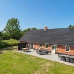 Ein Haus mit Terrasse, Liegestühlen und Grillplatz im Freien.