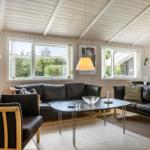Wohnzimmer mit zwei schwarzen Sofas, einem ovalen Tisch und Holzwänden.