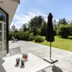 Terrasse mit Tisch, Stühlen und Sonnenschirm. Blick auf grünen Garten und Bäume.