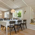 Esszimmer mit Tisch, Stühlen und Fenstern. Eckbank mit Kissen. Holzwände und Boden.