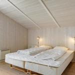 Schlafzimmer mit Holzwand, Doppelbett und Wandlampen.