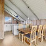 Esszimmer mit Holztisch, Stühlen und Küchenbereich unter schrägem Dach.
