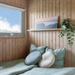 Schlafzimmer mit Holzwand, Bett, Kissen und Fenster mit Blick.