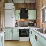 Küche mit Holzwänden, mintgrünen Schränken und moderner Arbeitsplatte.