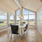 Esszimmer mit Tisch, Stühlen und großen Fenstern. Holzwände und Boden.