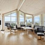 Wohnzimmer mit Holzboden, großen Fenstern und schwarzer Ledermöbelgruppe.