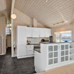 Küche mit weißer Einbauküche, Glasfrontschrank und Holzwandverkleidung.