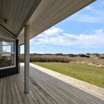 Terrasse mit Holzboden und Sicht auf Grasland und Häuser im Hintergrund.