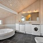 Badezimmer mit Whirlpool, Waschmaschine und Trockner. Holzwand und dunkler Boden.
