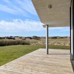 Terrasse mit Holzdecke und Blick auf Grasland und Ferienhäuser.