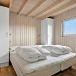 Schlafzimmer mit Holzwandverkleidung, weißem Bett und Fenster mit Blick auf den Himmel.