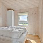 Schlafzimmer mit Holzwand, Bett, Fenster und Schrank.