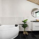 Badezimmer mit Badewanne, Waschbecken und Pflanze.