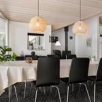 Essbereich mit runder Tafel, schwarzen Stühlen und zwei hängenden Lampen.
