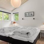 Schlafzimmer mit Doppelbett, zwei Fenstern und Nachttisch mit Lampe.