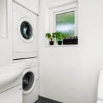 Waschmaschine und Trockner in einem Raum mit Waschbecken und Toilette.