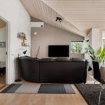 Wohnbereich mit Sofa, TV und Essbereich unter Holzdecke.