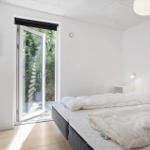 Schlafzimmer mit Bett, Schrank und Glastür zum Garten.
