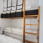 Doppelstockbett mit Matratzen und Leiter. Neben einem Bett steht ein Nachttisch.