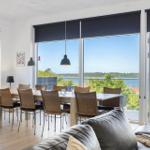 Essbereich mit Blick auf Wasser und Wald. Tisch, Stühle und große Fenster.