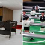 Fußballtisch mit Spielern und Kugel in einem Raum mit brauner Ledercouch.