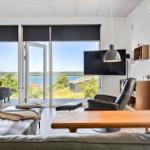Wohnzimmer mit Aussicht auf Wasser und Garten. Sofa, Couchtisch und Fernseher.