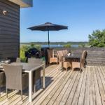 Terrasse mit Essbereich, Grill und Blick auf Wasser und Wald.