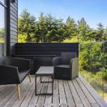 Terrasse mit zwei Sesseln und Tisch, Blick auf Wald und Himmel.