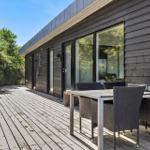 Terrasse mit Tisch und Stühlen neben modernem Holzhaus mit großem Fenster