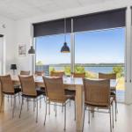 Essbereich mit Tisch und Stühlen. Große Fenster mit Blick auf Wasser und Wald.