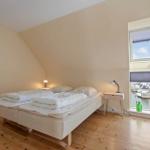 Schlafzimmer mit Doppelbett, Fensterblick auf Hafen und Holzboden.