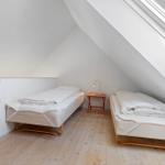 Zwei Betten in einem Dachzimmer mit Holzboden und Dachfenster.