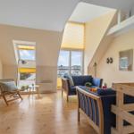 Wohnzimmer mit Holzboden, Sofa und Blick auf Hafen