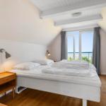 Schlafzimmer mit Blick aufs Meer, Holzboden und weißem Bett.