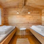 Zwei Betten in einem Holzhaus mit Fenster und Tisch