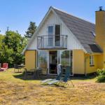 Gelbes Haus mit Balkon und Gartenmöbeln. Terrasse mit Tisch und Stühlen. Hintergrund: Bäume.