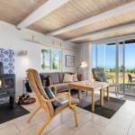 Wohnzimmer mit Kamin, Sofa und Blick aufs Meer.