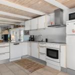 Küche mit weißen Schränken, Kühlschrank und Blick aufs Meer.