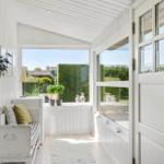 A white interior space with a view of a green garden and a door.