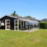 Black house with glass conservatory, green lawn, and hedges in the background.