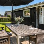 Terrace with table, chairs, and umbrella. Backyard with lawn and sea view.