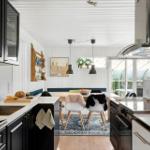 Kitchen with dining area, black cabinets, wooden chairs, and window to terrace.