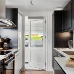 Kitchen with black cabinets, white countertop, and door to the garden.