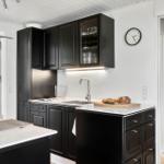 Kitchen with black cabinets, white countertop, and integrated sink.