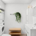 Bathroom with washing machine, mirror, and plants on the wall.