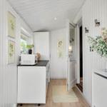 Bright kitchen with microwave and plants on walls. Wooden floor and white walls.
