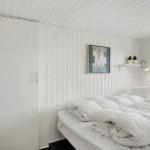 Bedroom with white bed, wall art, and window. Gold mirror on the wall.