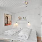 Two beds with white bedding in a room with white walls and ceiling.
