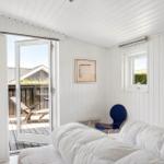 Bedroom with white walls, bed, and terrace door. Blue chair and pictures on the wall.